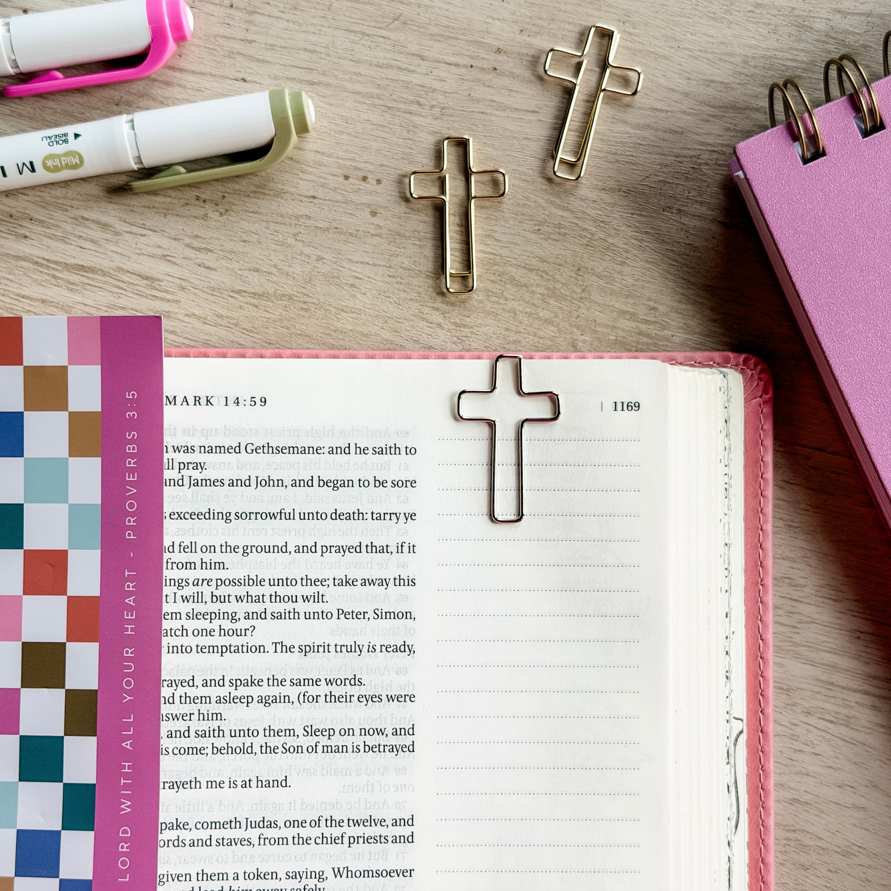 Open book with cross bookmarks on a wooden surface