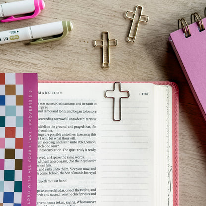 Open book with cross bookmarks on a wooden surface