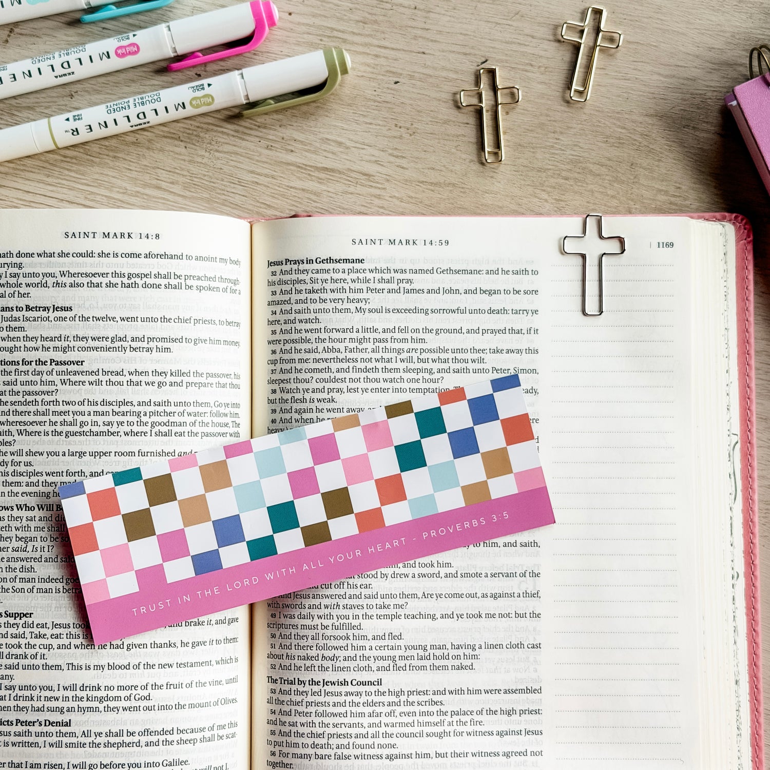 Open book with colorful bookmark and cross-shaped bookmarks on a wooden surface