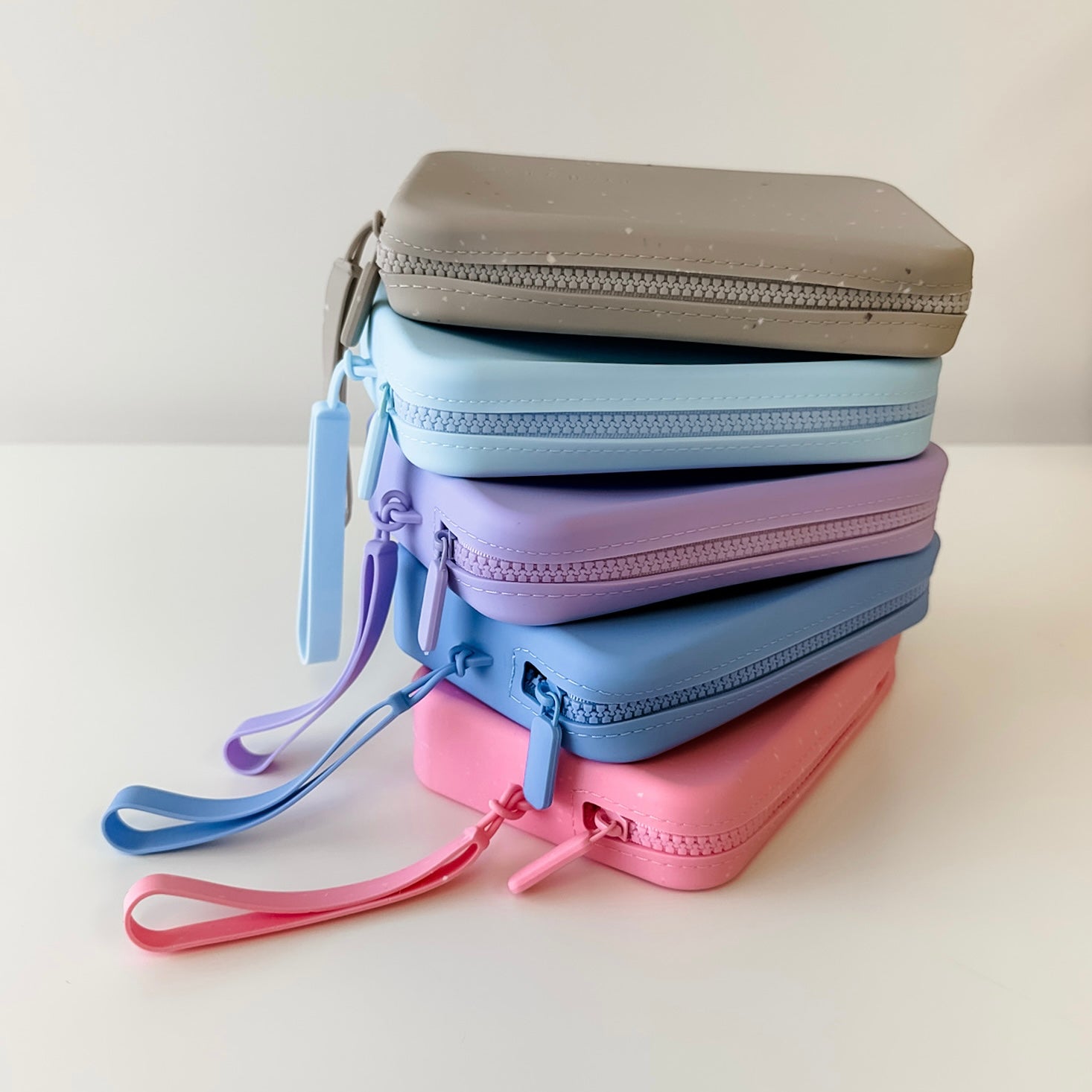 Stack of pastel-colored zippered pouches on a light background