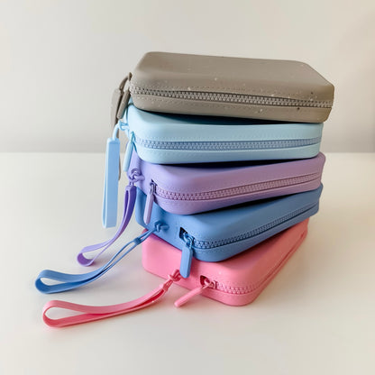 Stack of pastel-colored zippered pouches on a light background