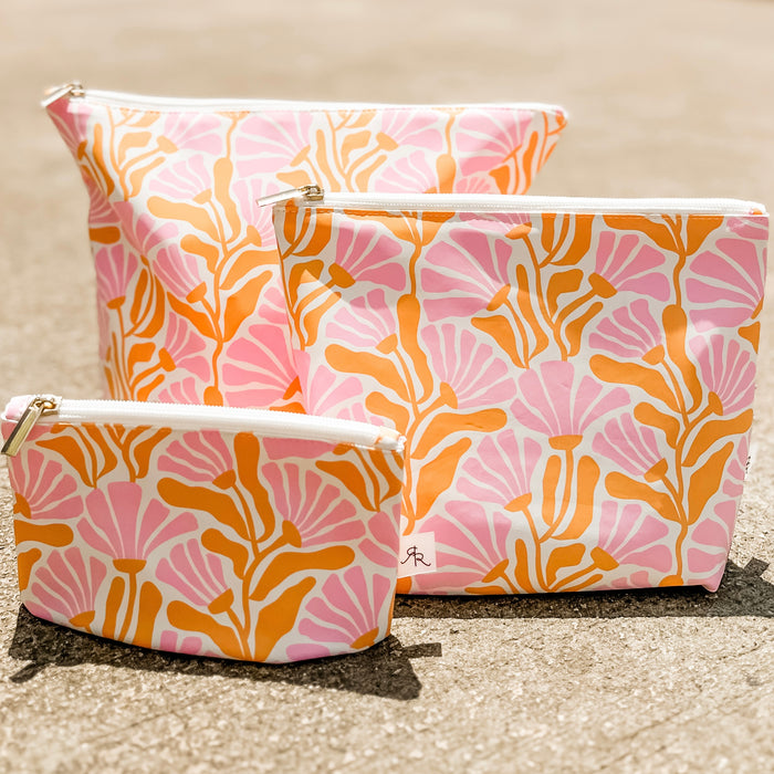 Three pouches with pink and orange floral pattern on a beige background