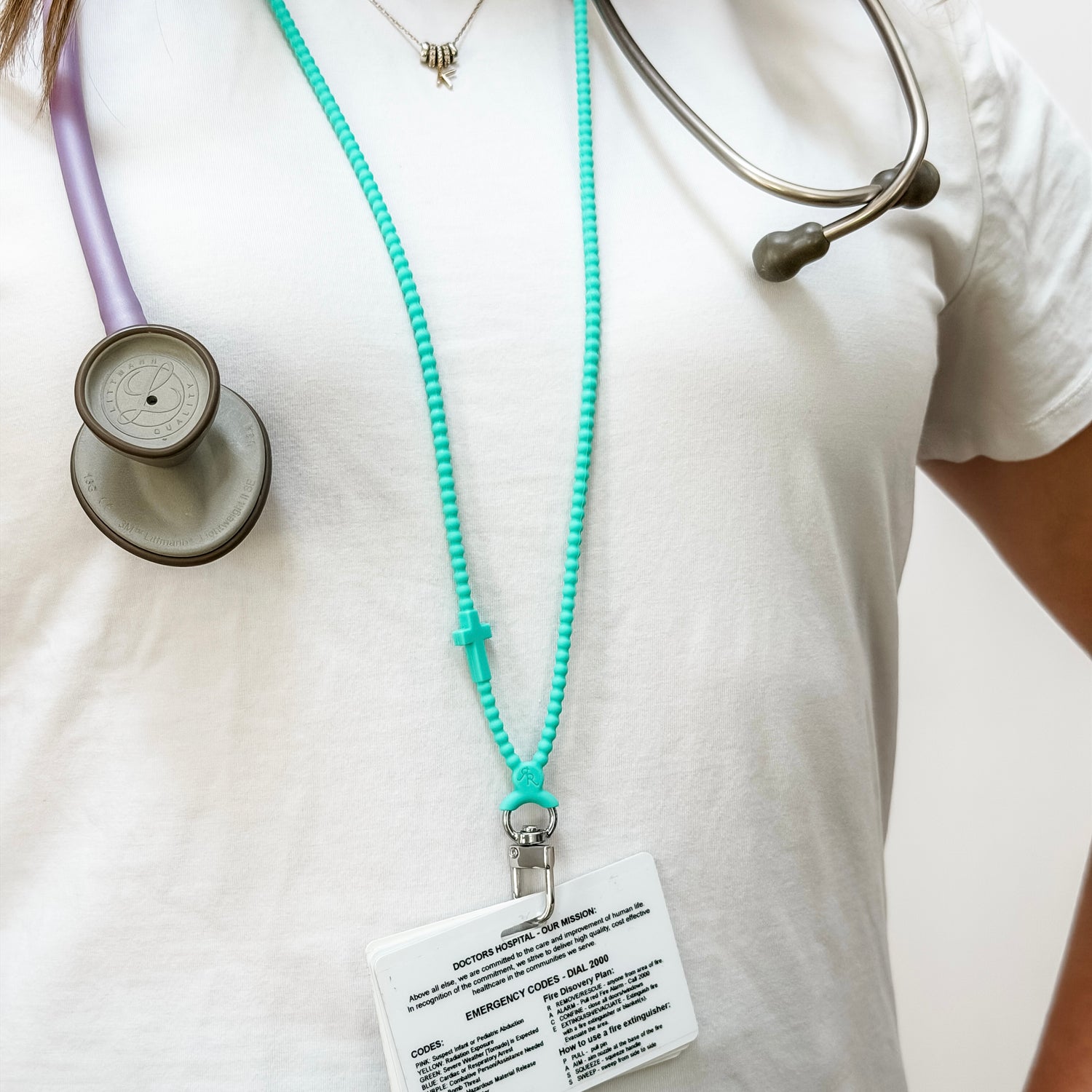 Person wearing a stethoscope with a turquoise lanyard and badge on a white background