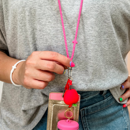 Person holding a pink lanyard with a red charm and keychain holder.