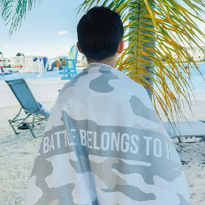 Person wrapped in a camouflage towel with text on a beach