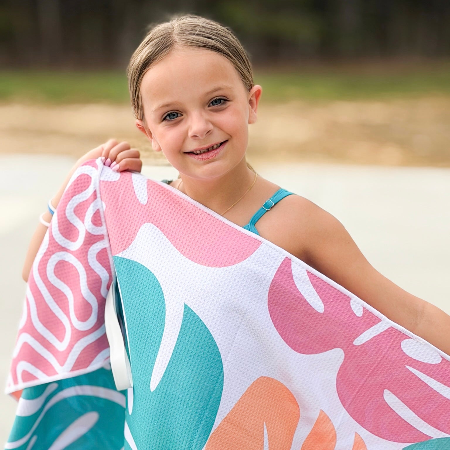 Young girl holding a colorful towel with leaf patterns outdoors