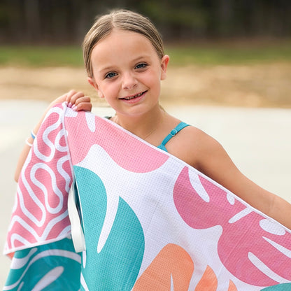 Young girl holding a colorful towel with leaf patterns outdoors