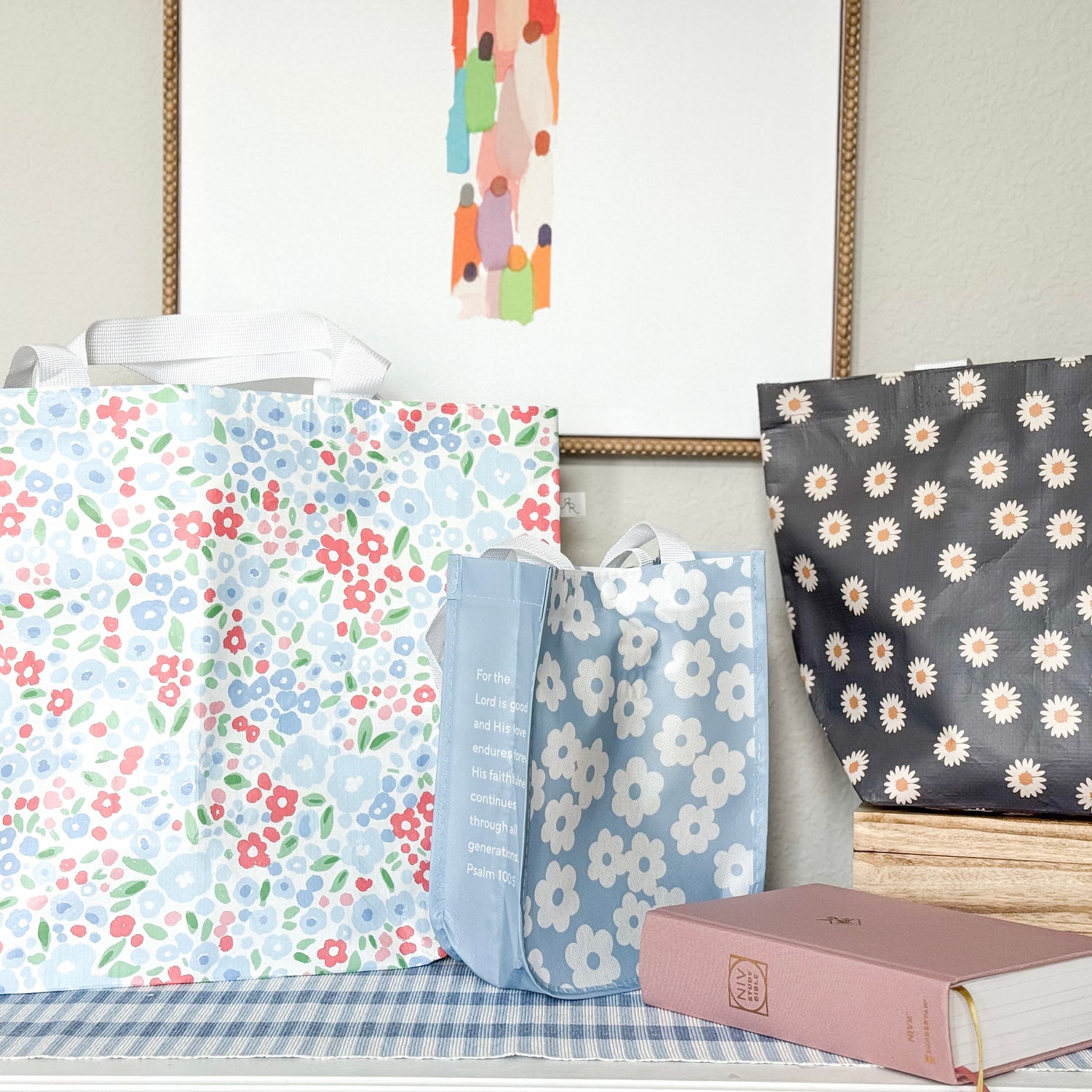 Three floral-patterned bags on a surface with a book in the foreground.