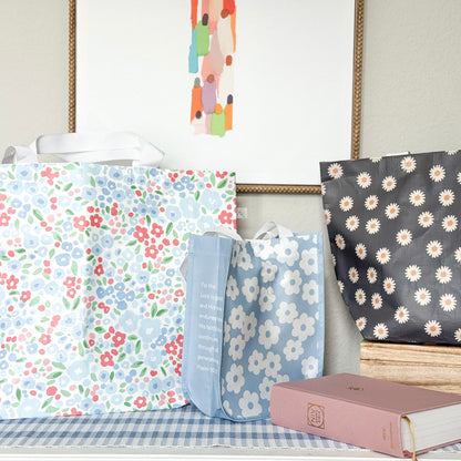 Three floral-patterned bags on a surface with a book in the foreground.