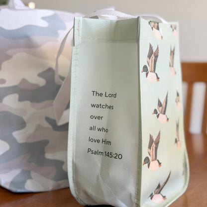 Light blue tote bag with duck design and inspirational quote on a wooden surface