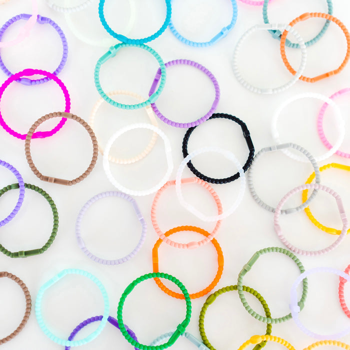 Colorful Jesus bracelets scattered on a white background