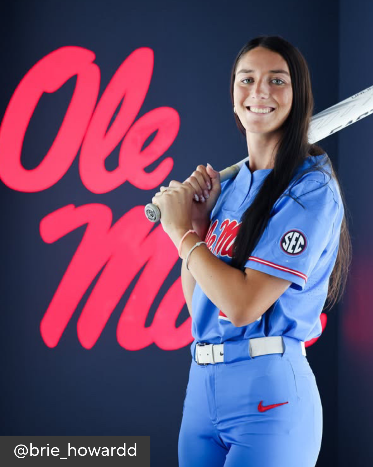 Woman athlete holding a bat for a photo