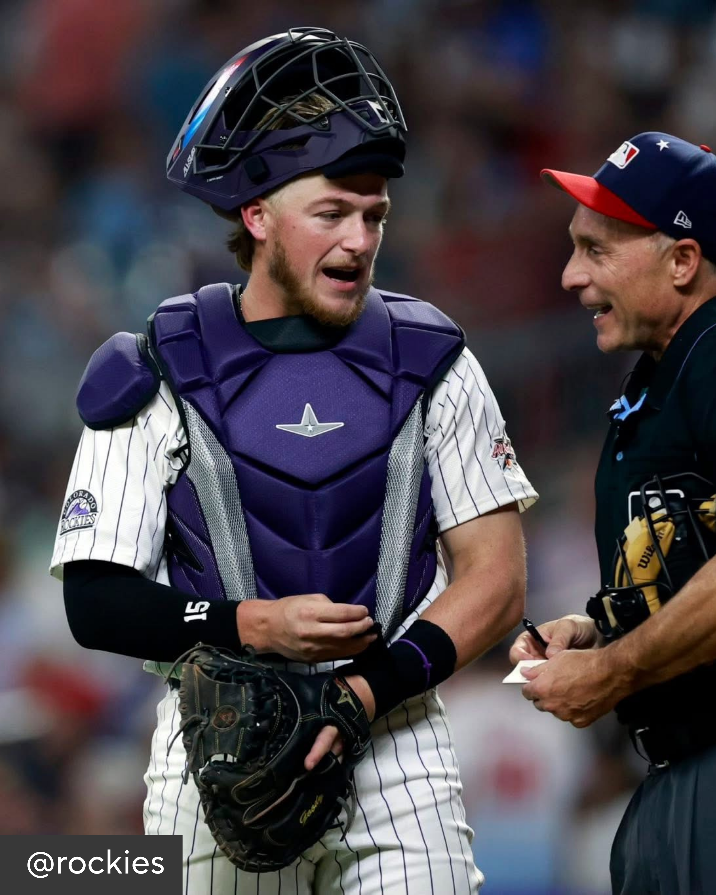 Baseball player in catcher's gear talking to an umpire during a game.