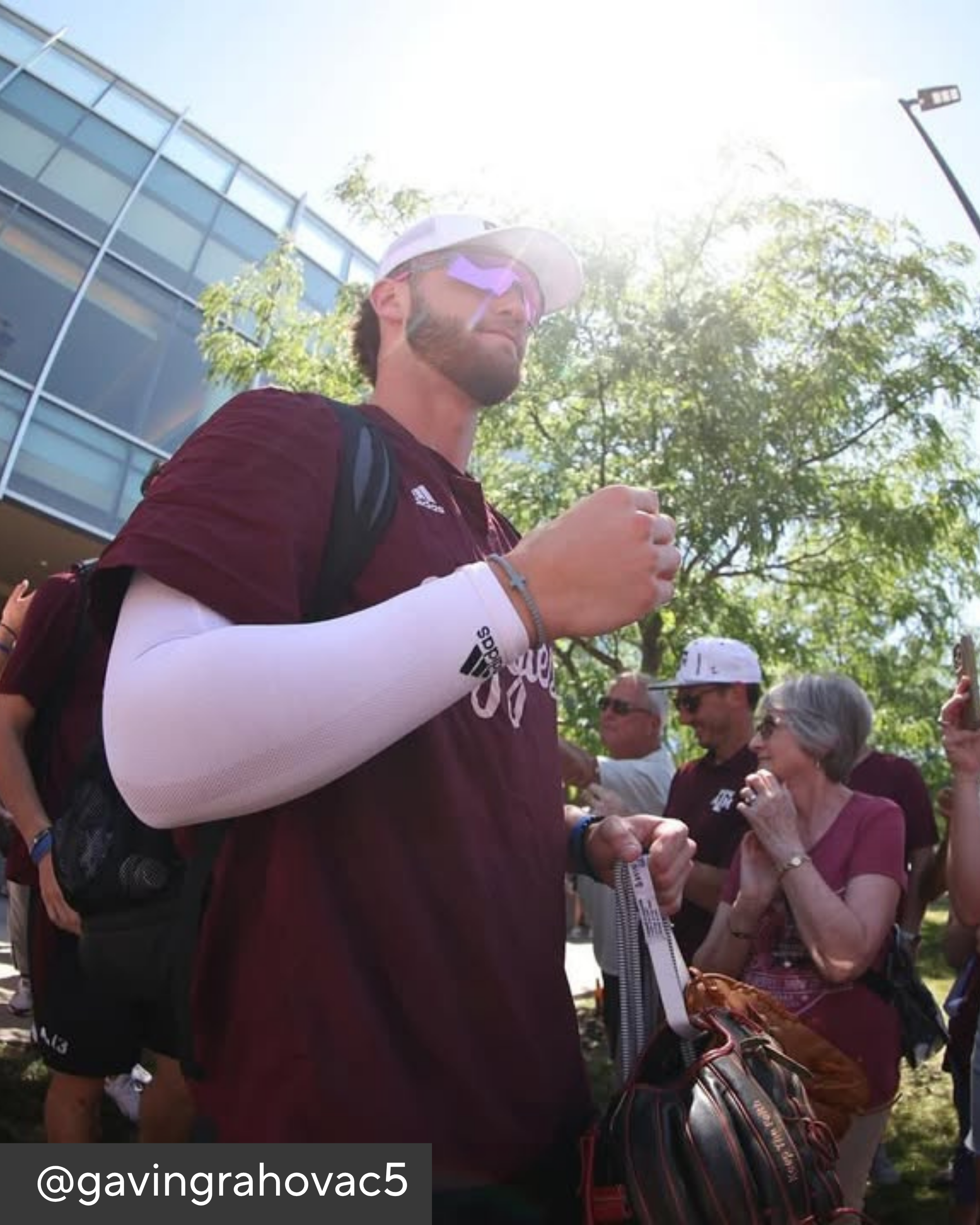 Person in maroon shirt with white arm sleeve holding a phone outdoors