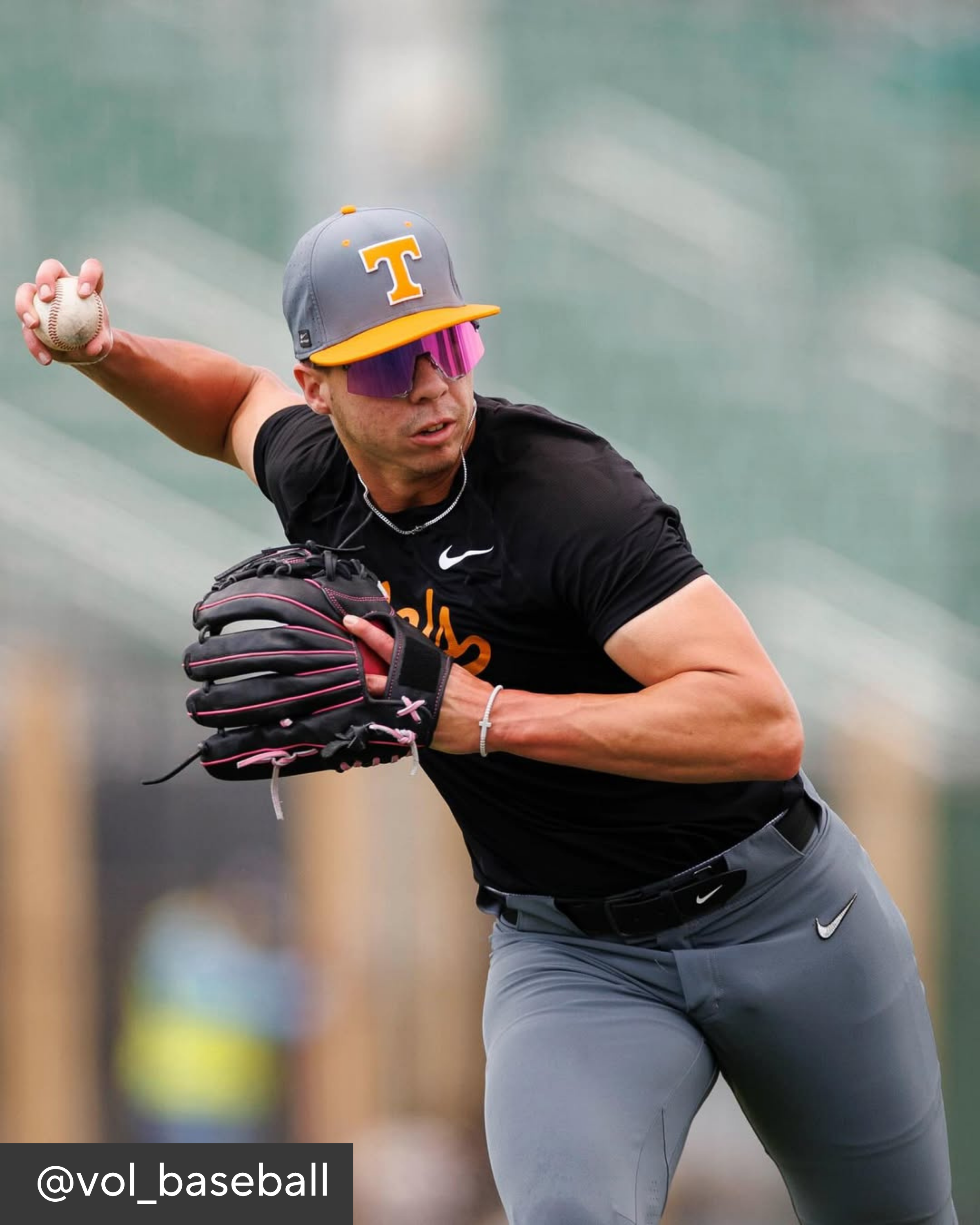 Baseball player in action wearing a black shirt, gray pants, and a gray cap with a yellow 'T'.