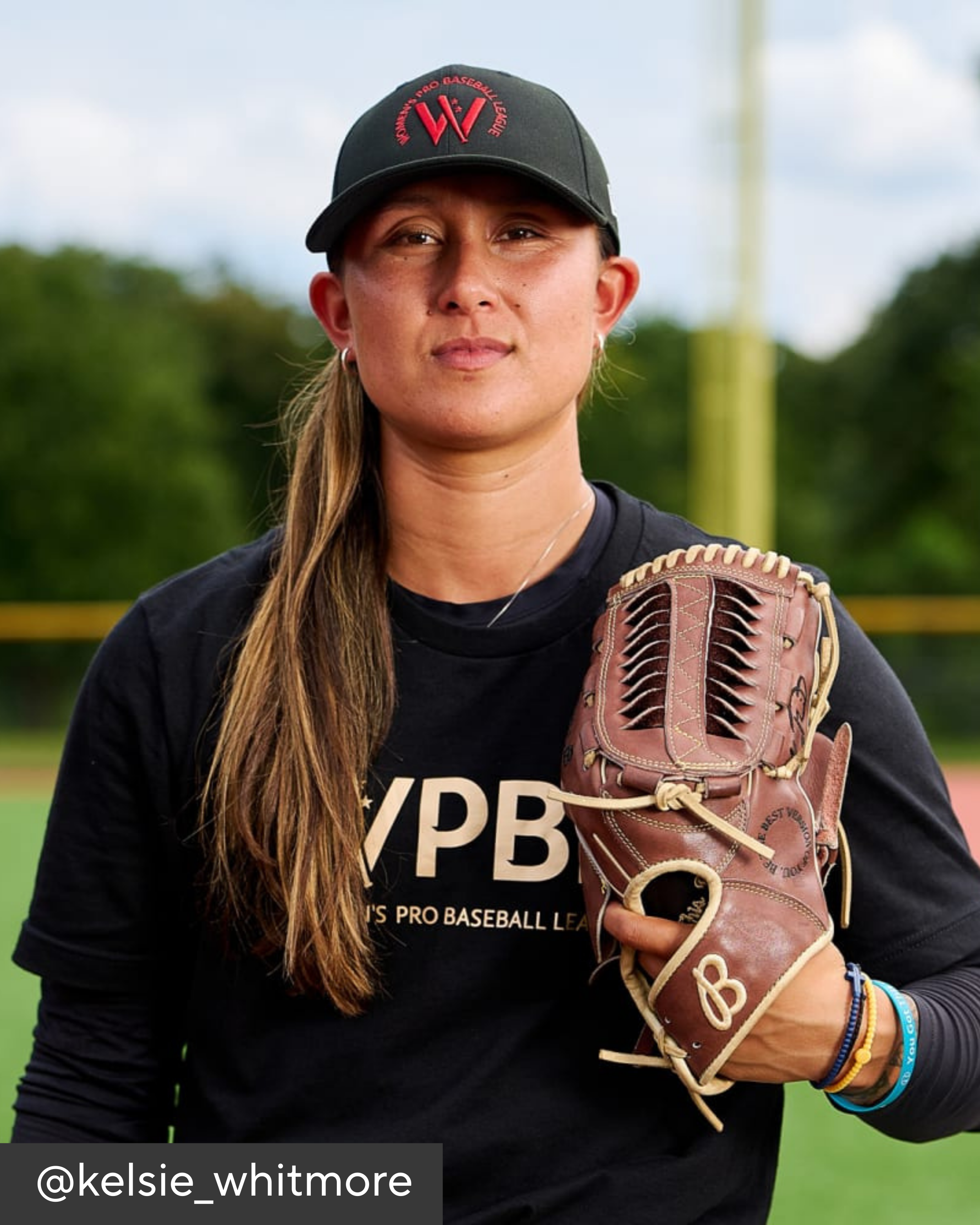 Person wearing a black cap and holding a baseball glove on a sports field