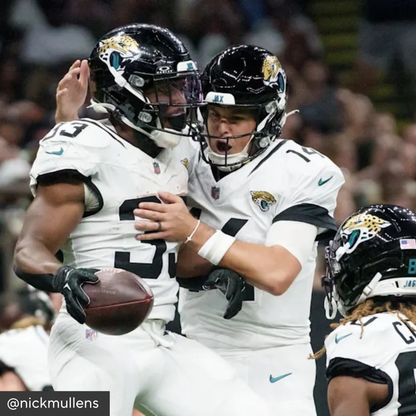 Two football players in Jacksonville Jaguars uniforms celebrating on the field.