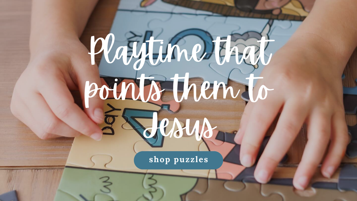 A close-up of a child's hands assembling a colorful children's jigsaw puzzle on a wooden table, with overlaid text reading 'Playtime that points them to Jesus' and a 'shop puzzles' button.