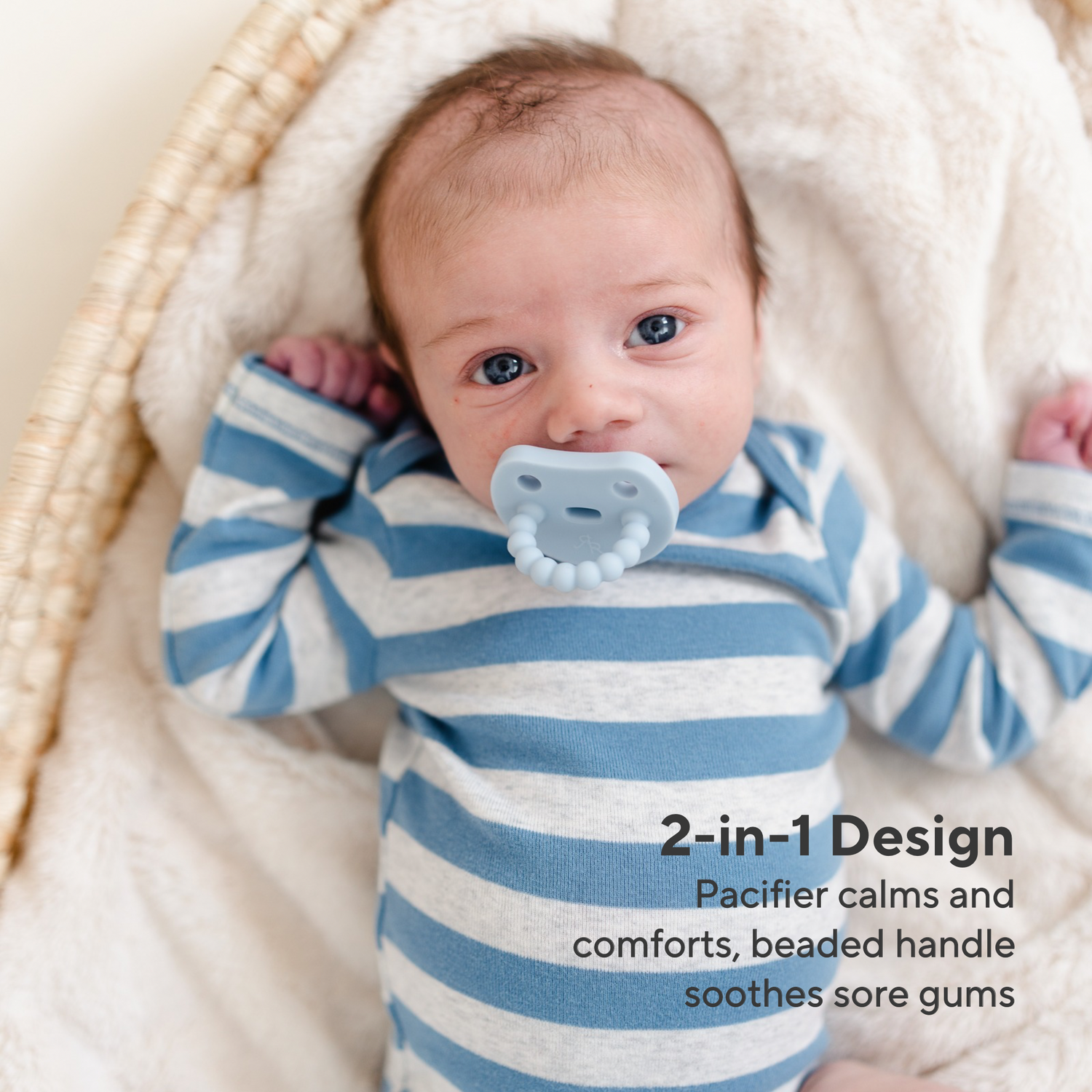 A baby wearing a blue and white striped long-sleeve bodysuit lies in a woven basket on a cream blanket, with a pale blue pacifier in their mouth. Text on the image reads &