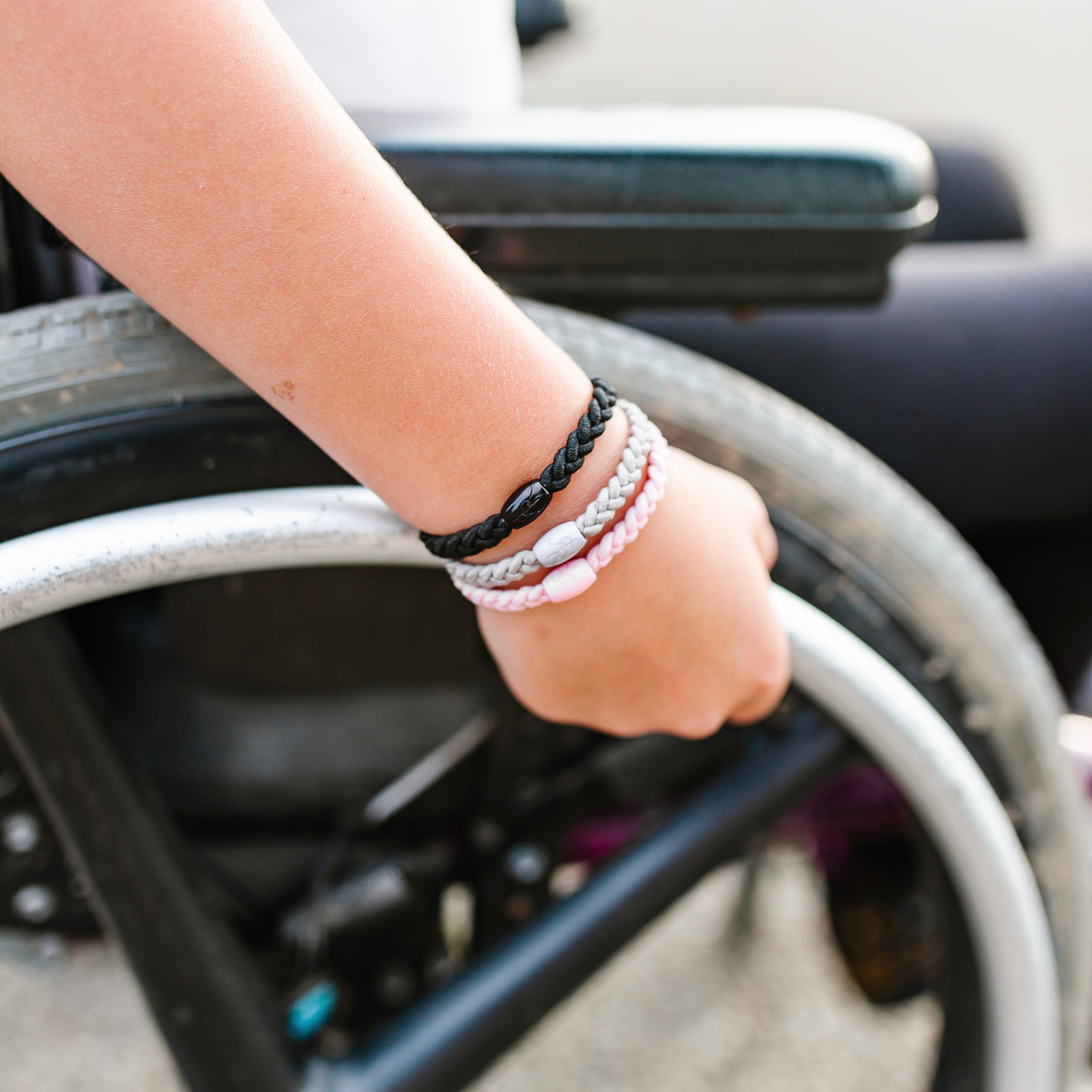 Girl in a wheelchair modeling the Black, Grey and Pink Cutie Bands on her wrist.