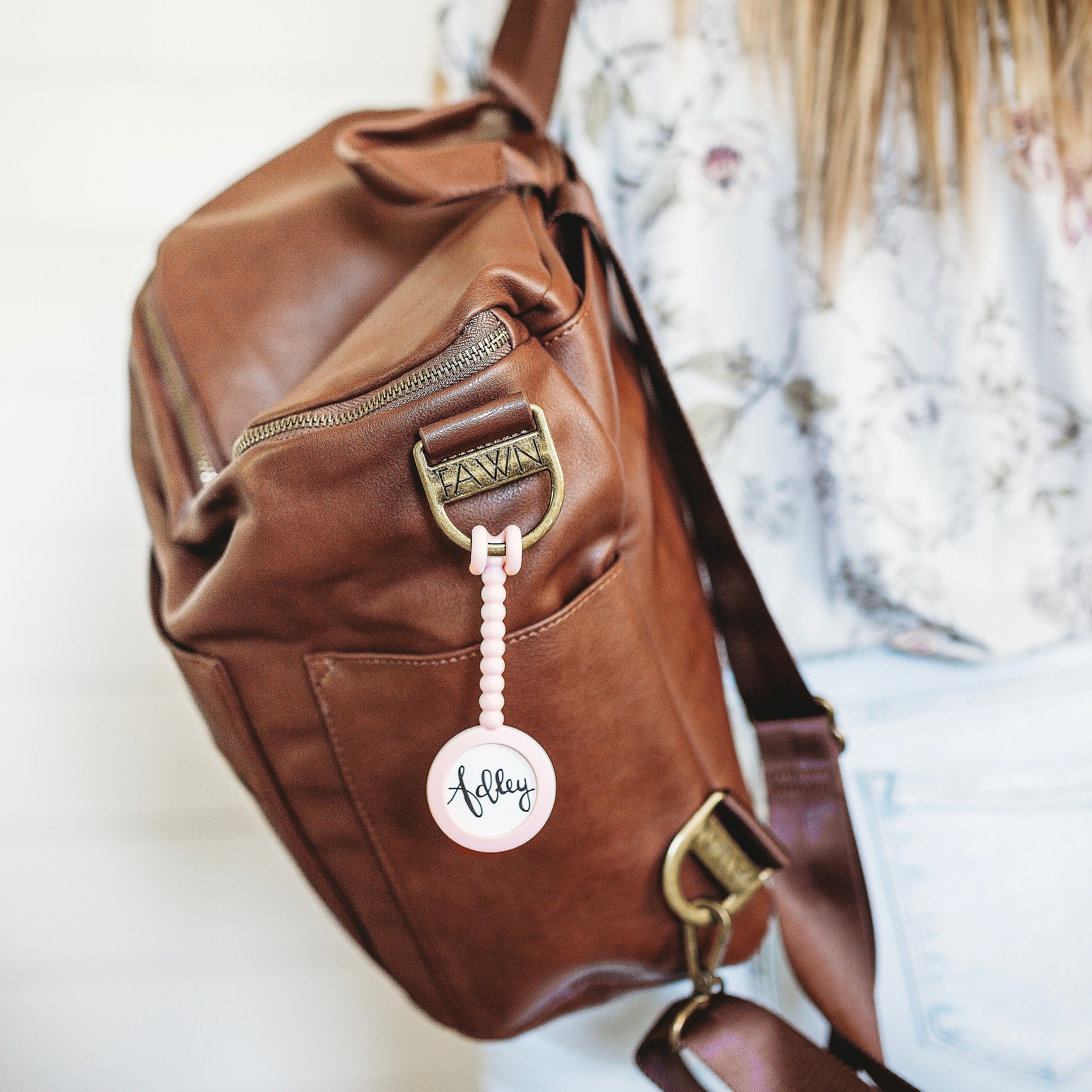 Mom wearing a diaper bag with a Cutie Tag attached.