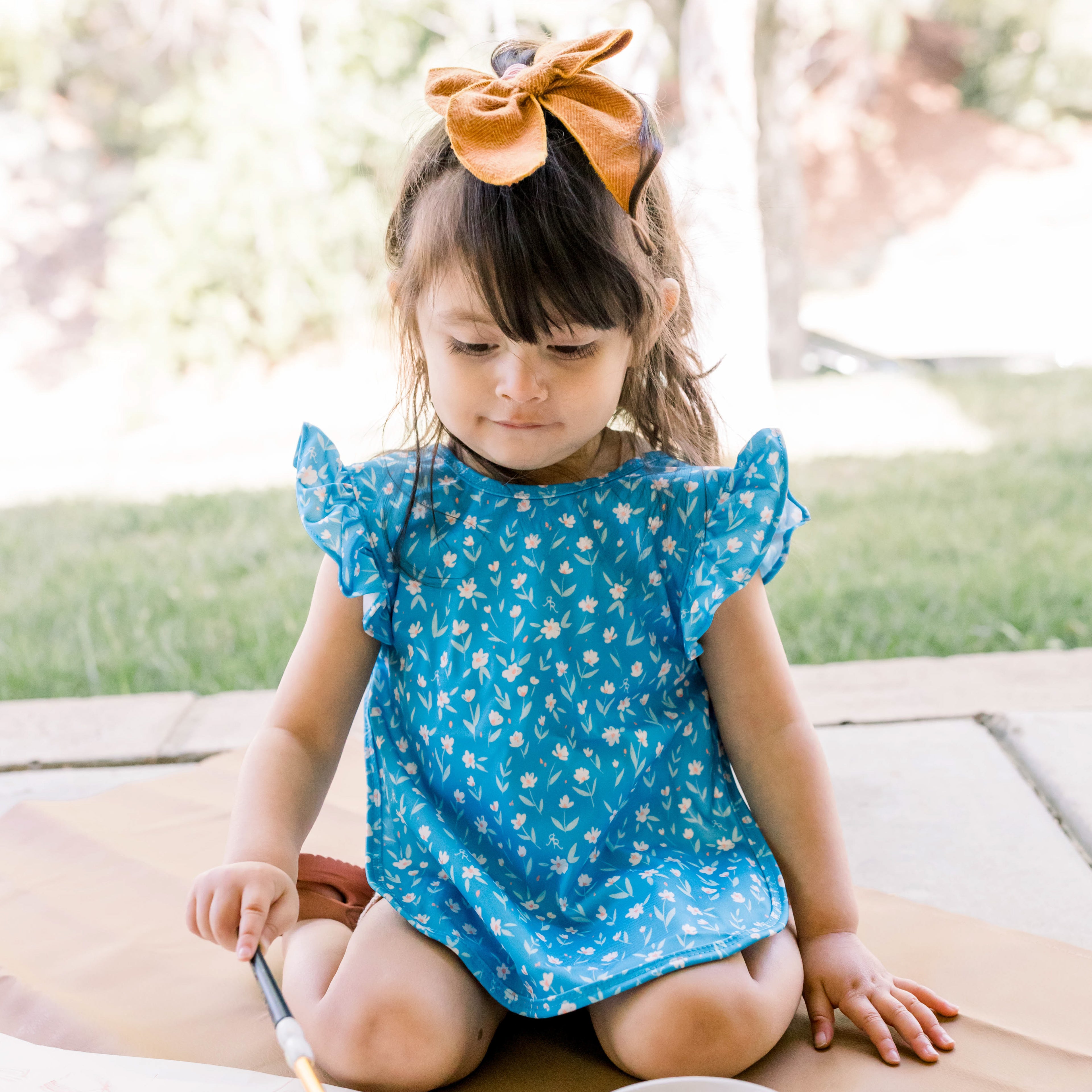 Girl painting and wearing the Blue Daffodil Cutie Bapron.