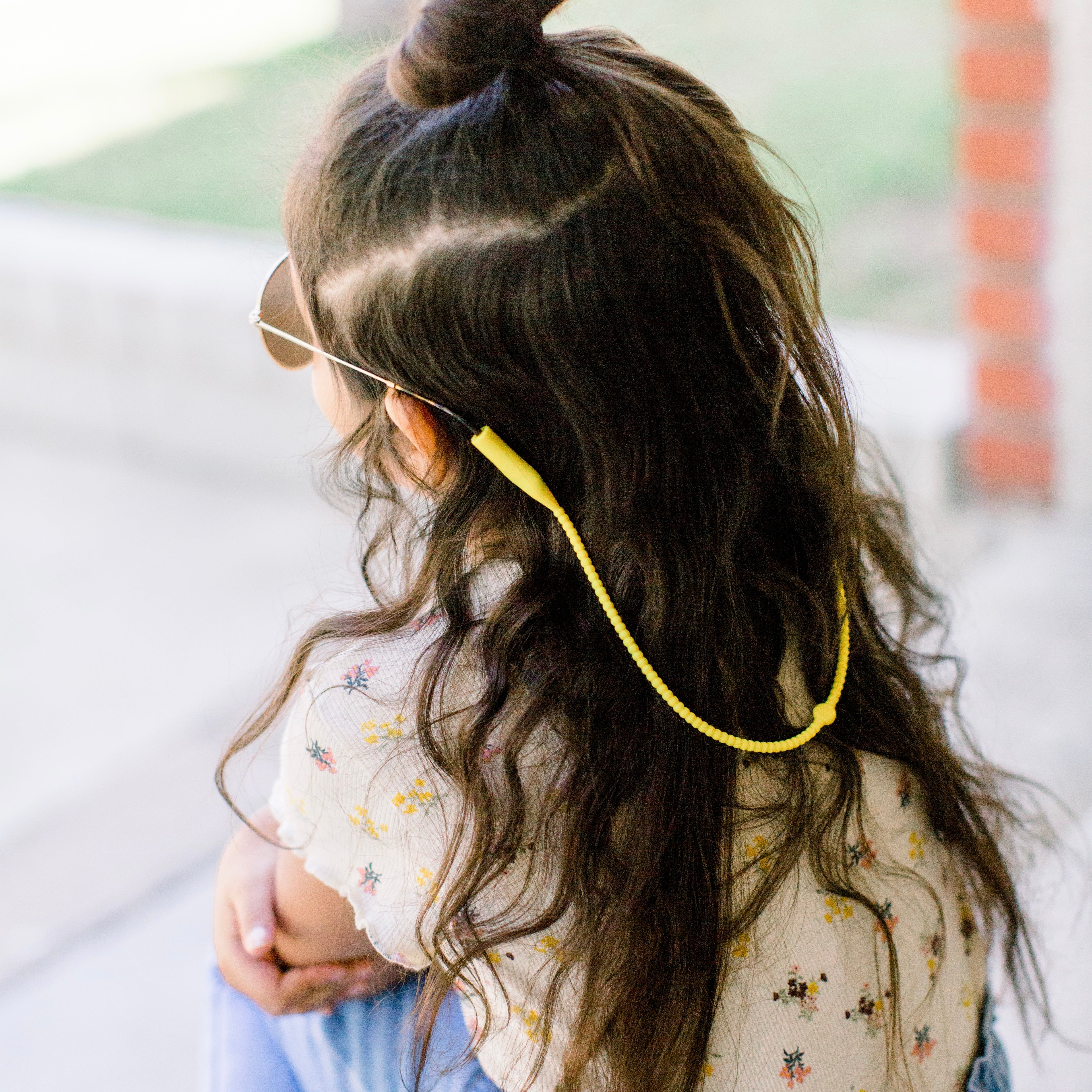 Girl wearing the Sunshine Cutie Straps attached to her sunglasses.