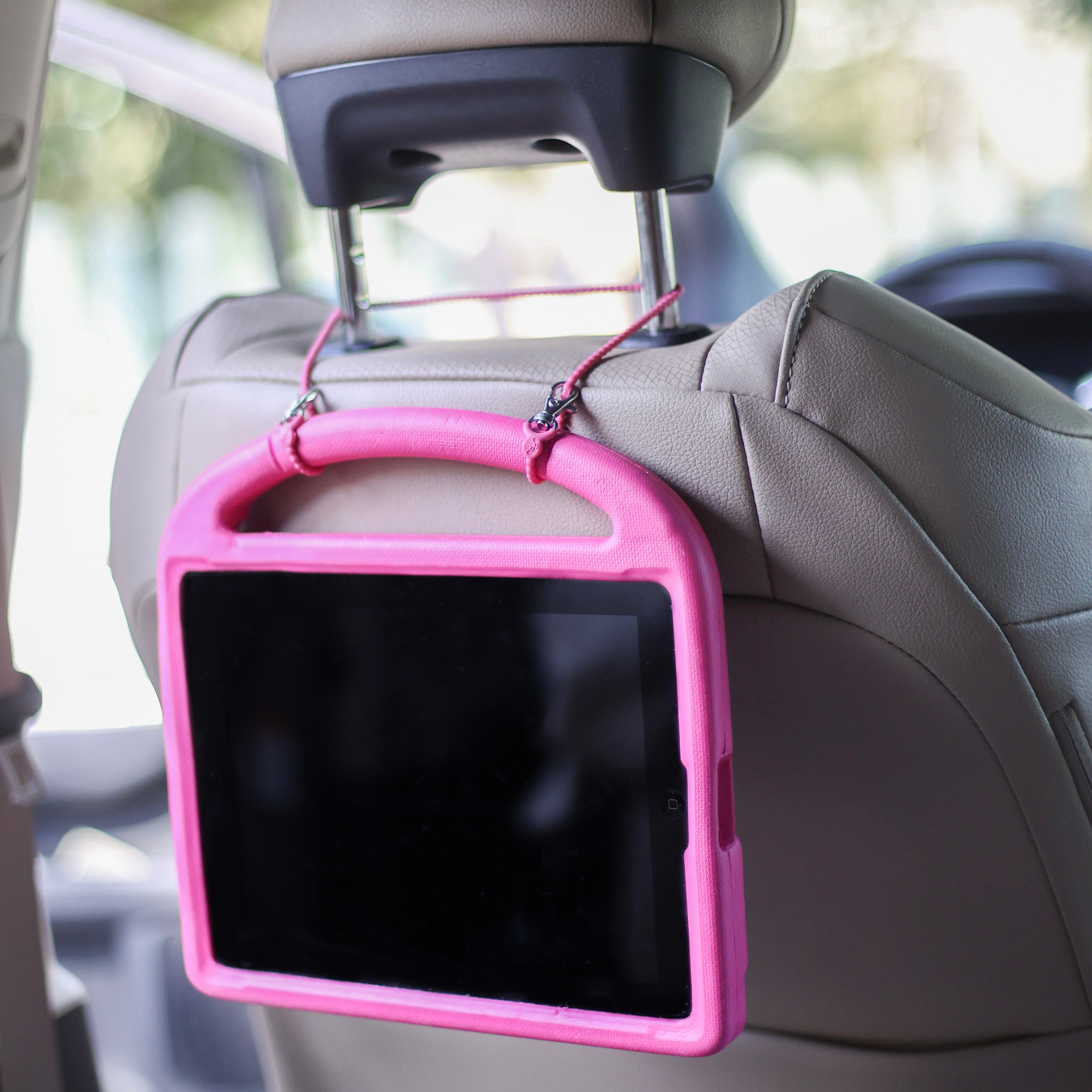 Cutie Clasp attached to a car head rest holding a tablet.