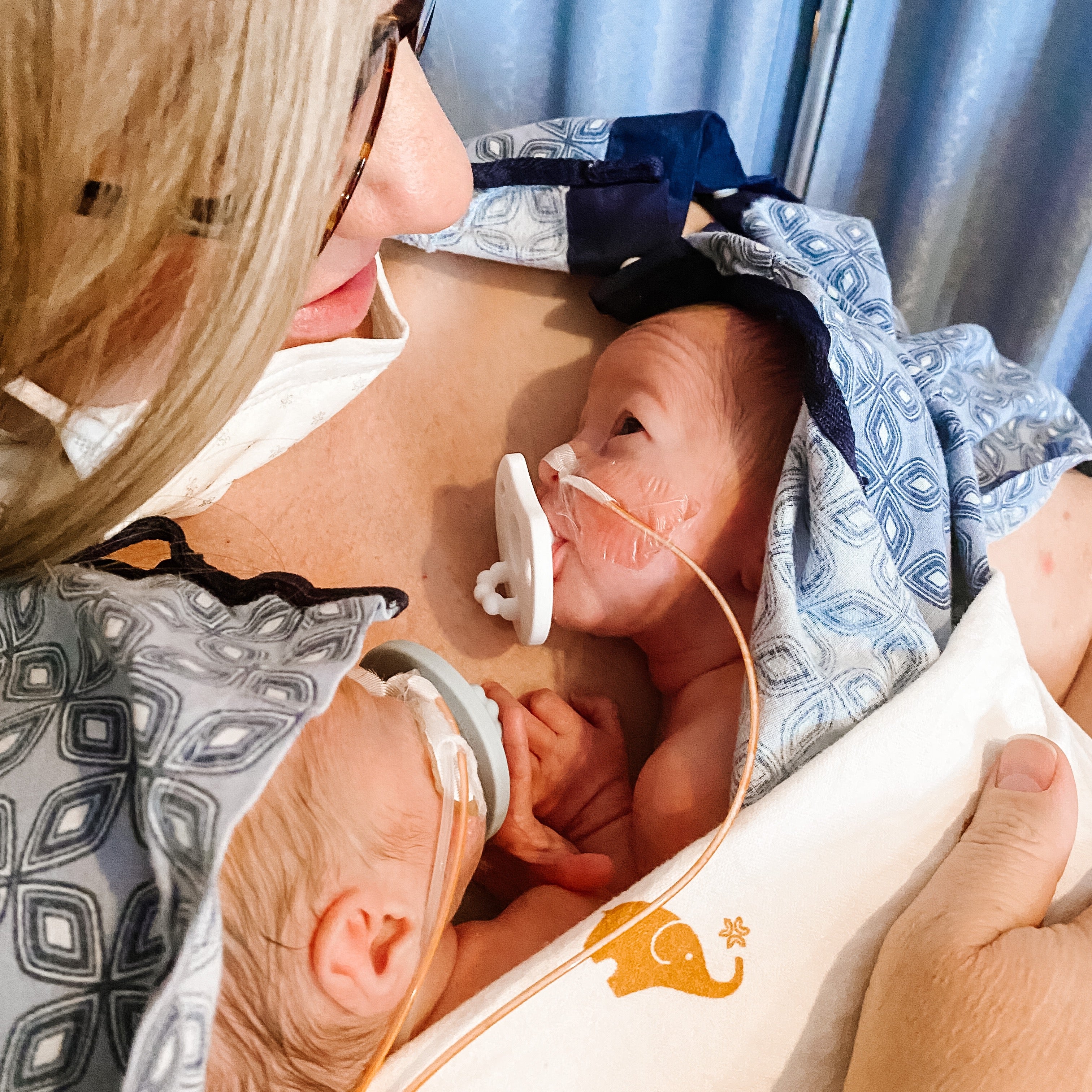 Newborn twins doing chest-to-chest on their mother while using the White Cutie Preemie.