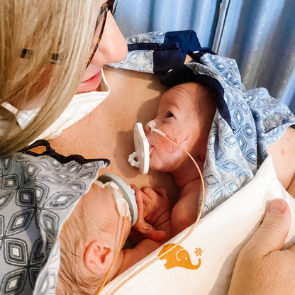 Newborn twins doing chest-to-chest on their mother while using the White Cutie Preemie.